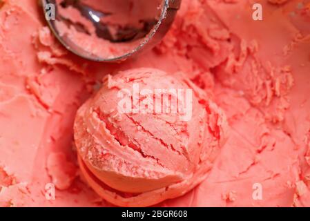 Naturale fatto in casa di frutti di bosco appena cotti freddo gelato dolce dessert di colore corallo con scoop metallico come sfondo alimentare, copia spazio. Vista dall'alto. Foto Stock