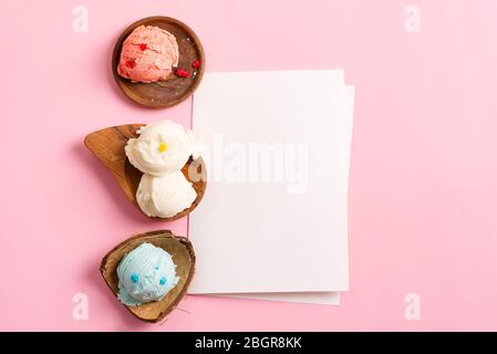Palle di gelato naturale fresco e freddo fatto in casa o gelato nelle conchiglie biologiche legnose con foglio di carta su un dorso rosa pastello con copia Foto Stock