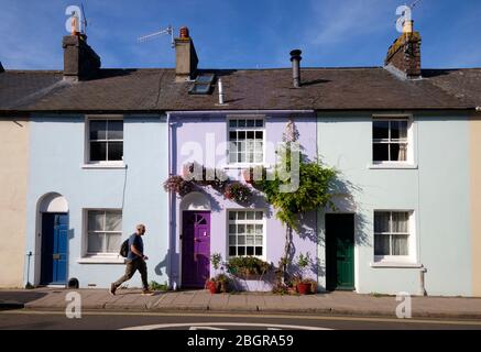 Uomo che cammina sul marciapiede da una fila colorata di case a Lewes East Sussex Foto Stock