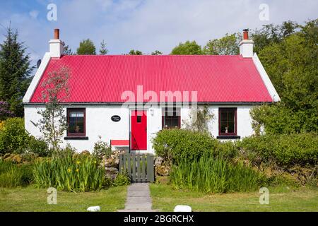 Caratteristico cottage tradizionale imbiancato a calce con luminoso porta di fronte rosso e tetto in ferro ondulato a Kilberry, Argyll e Bute, Scozia Foto Stock