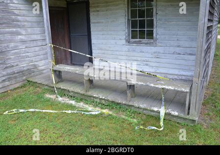 usurato o intemperie vecchia casa di legno con nastro giallo e non entrare segno sul portico Foto Stock