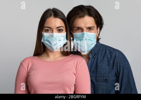 Ritratto di giovane uomo e donna che indossa maschere mediche guardando la macchina fotografica Foto Stock