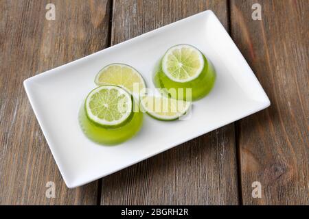 Gelatina verde con fette di lime al limone su sfondo di legno Foto Stock