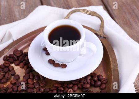 Tazza di caffè fresco su vassoio ovale in metallo su tovagliolo bianco su sfondo in legno Foto Stock