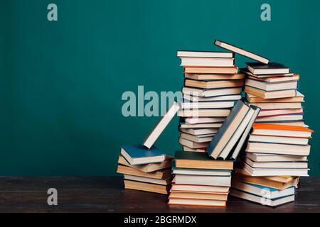 molti pile di libri didattici nella biblioteca universitaria su sfondo verde Foto Stock