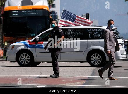 Los Angeles, California, Stati Uniti. 22 aprile 2020. Un poliziotto che indossa una maschera facciale dirige il traffico durante una protesta della carovana di un veicolo per invitare funzionari statali e locali a riaprire l'economia durante l'epidemia di coronavirus nel centro di Los Angeles, mercoledì 22 aprile 2020. Credit: Ringo Chiu/ZUMA Wire/Alamy Live News Foto Stock