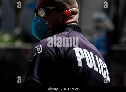 Los Angeles, California, Stati Uniti. 22 aprile 2020. Un poliziotto che indossa una maschera facciale dirige il traffico durante una protesta della carovana di un veicolo per invitare funzionari statali e locali a riaprire l'economia durante l'epidemia di coronavirus nel centro di Los Angeles, mercoledì 22 aprile 2020. Credit: Ringo Chiu/ZUMA Wire/Alamy Live News Foto Stock