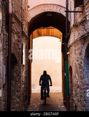 Sihouette di un ciclone che scende lungo uno dei numerosi vicoli stretti di Foligno, Umbria, Italia Foto Stock