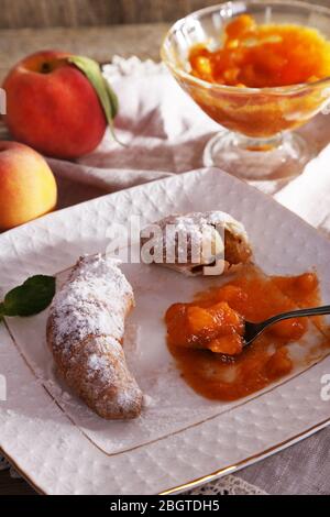 gustosa marmellata di albicocche e croissant su tavolo di legno Foto Stock