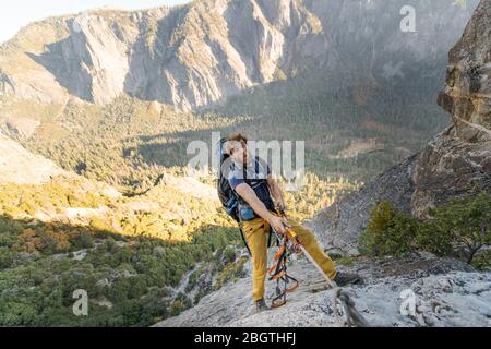 Uomo che si ggiola corda su El Capitan facendo divertente viso con zaino Foto Stock