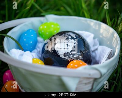 Terra globo seduto in un cestino di Pasqua pieno di polka uova punteggiate. USA mappa in un cestino di Pasqua. Foto Stock