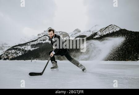 il giocatore di hockey in tuta smette di dare il calcio veloce sullo spruzzo congelato sul lago Foto Stock