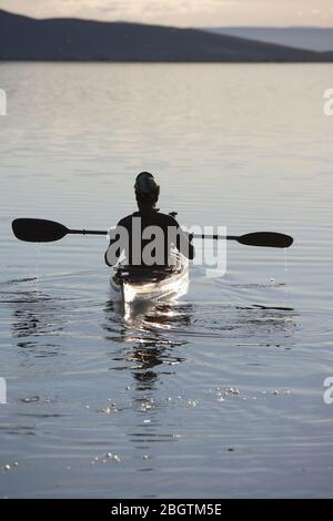 Uomo che gode la serenità del lago Myvatn sul suo kayak di mare Foto Stock