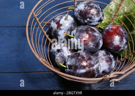 Prugne dolci mature in cesto di metallo, su tavola di legno Foto Stock