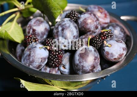 Prugne dolci mature in colapasta metallica, su tavola di legno Foto Stock