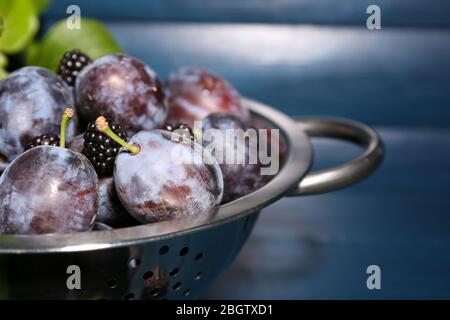 Prugne dolci mature in colapasta metallica, su tavola di legno Foto Stock