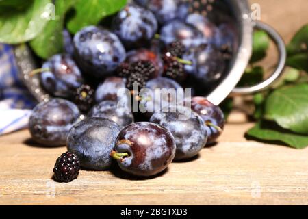 Prugne dolci mature in colapasta metallica, su tavola di legno Foto Stock