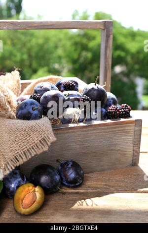 Prugne dolci mature in cassa di legno, su sfondo naturale Foto Stock