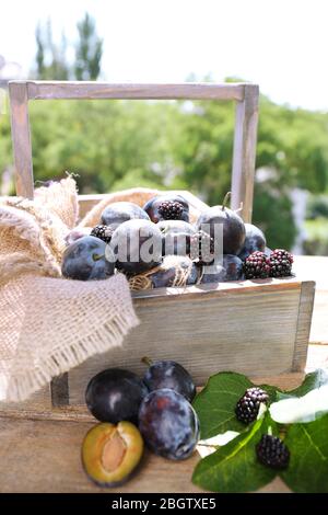 Prugne dolci mature in cassa di legno, su sfondo naturale Foto Stock