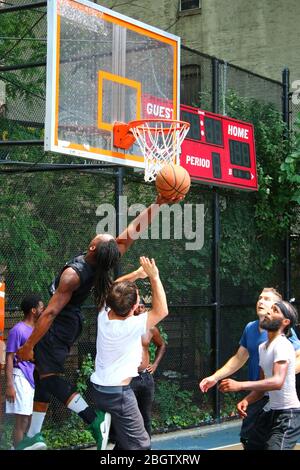 Giocatori dilettanti che si scrambling per la palla sotto il tabellone mentre giocano a basket in 'The Cage', West 4th Street Courts, Manhattan il 29 LUGLIO 2019 i Foto Stock