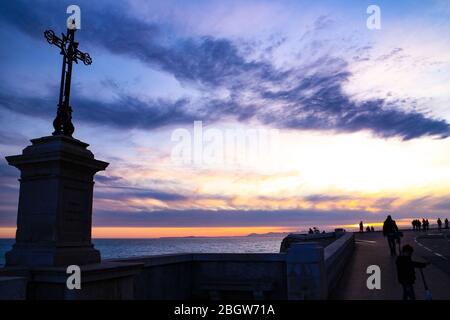 Passeggiata al tramonto al Quai Rauba Capeu sotto la collina del Castello, con una sagoma a croce, la costa mediterranea e un cielo spettacolare. Foto Stock