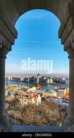 Il paesaggio urbano di Budapest con parti di Buda e Pest, il Parlamento ungherese e il Danubio, incorniciato naturalmente in un arco di pietra del Bastione dei pescatori. Foto Stock