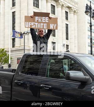 Albany, NY - 22 aprile 2020: Un uomo che tiene un poster partecipa alla protesta operazione Gridlock fuori del palazzo del governo dello stato di New York Foto Stock