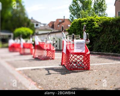 Strasburgo, Francia - 13 aprile 2020: Obiettivo tilt-shift vista sopra la barriera di delimitazione dei carrelli dei supermercati nel grande parcheggio del negozio di alimentari moderno centro commerciale durante Covid-19 coronavirus pademy - non parcheggiare segno Foto Stock