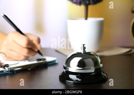 Scrittura a mano femminile nel libro degli ospiti dell'hotel alla reception, su sfondo luminoso Foto Stock