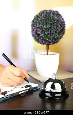 Scrittura a mano femminile nel libro degli ospiti dell'hotel alla reception, su sfondo luminoso Foto Stock