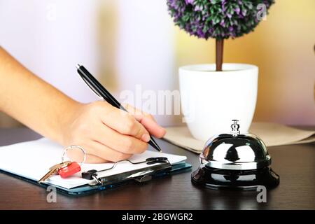 Scrittura a mano femminile nel libro degli ospiti dell'hotel alla reception, su sfondo luminoso Foto Stock