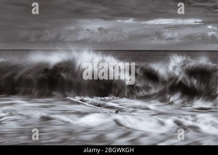 Rottura delle onde sulle vecchie difese del mare mono. Caister on Sea, dicembre 2018 Foto Stock