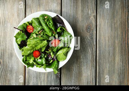 Insalata verde fresca in ciotola su tavolo di legno Foto Stock