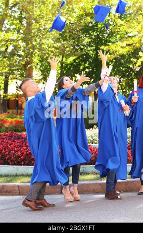 Studenti che lanciano cappelli di laurea in aria, all'aperto Foto Stock