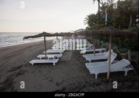 Malaga, Spagna. 22 aprile 2020. Sedie lunghe e ombrelloni sono visibili in una spiaggia vuota di Marbella, in mezzo alla malattia da coronavirus COVID-19. In seguito al confinamento decretato dal governo spagnolo per estendere la chiusura fino al 10 maggio, le persone sono ancora confinate nelle loro case causando una situazione eccezionale di scene urbane insolite come strade vuote o bar, ristoranti e negozi chiusi. Credit: SOPA Images Limited/Alamy Live News Foto Stock