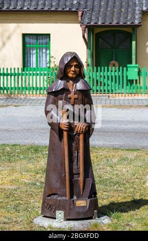 14 aprile 2020, Brandenburg, Schönborn/OT Lindena: La figura di un monaco con il segno 'sulle orme dei monaci di Dobrilugk' di Roland Karl si trova sul verde del villaggio. Foto: Soeren Stache/dpa-Zentralbild/ZB Foto Stock