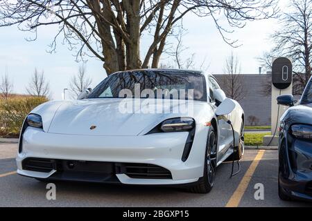 Bianco Porsche Taycan Turbo visto collegato, in carica presso una concessionaria Porsche. Foto Stock