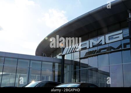 Il logo Mercedes-AMG appeso davanti a una concessionaria Mercedes-Benz in una giornata di sole. Foto Stock