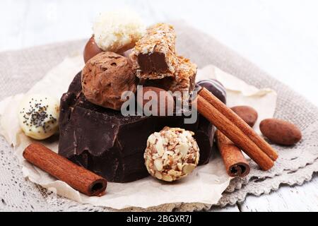 Mucchio di cioccolato e tartufi con bastone di cannella su carta sminuzzata, materiale grigio e sfondo ligneo Foto Stock