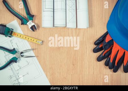 Rotoli di schemi elettrici e disegni di costruzione, protezione casco blu con i guanti e gli strumenti di lavoro, accessori per lavori di ingegnere, copia spazio f Foto Stock