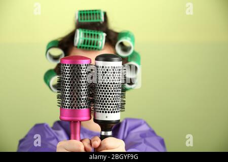 Ragazza in arricciacapelli tenendo pettini capelli su sfondo colorato Foto Stock