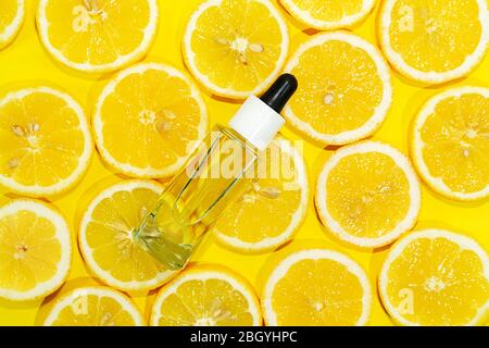 Siero naturale di vitamina c, prodotti di olio essenziale, per la cura della pelle. Cosmetica con fette di limone fresco e succoso su fondo di calce. Mock-up di prodotti di bellezza. Vista dall'alto, disposizione piatta Foto Stock