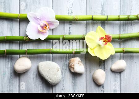 Fiori di Orchidea e bambù con pietre a pile su sfondo di legno Foto Stock