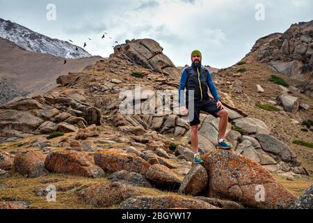 Ritratto di un runner maschio barbuto. Corre in alto in montagna. Percorso in corsa Foto Stock