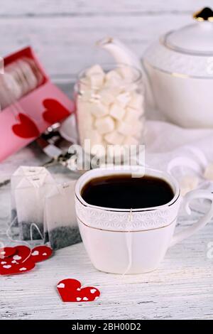 Tag teabag a forma di cuore, scatola e teacup su sfondo di legno Foto Stock