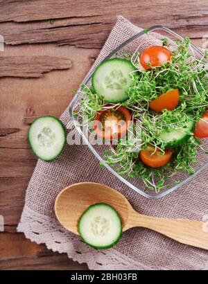 Insalata di caraffe con cetrioli a fette e pomodori ciliegini in una ciotola di vetro sullo sfondo rustico del tavolo in legno Foto Stock