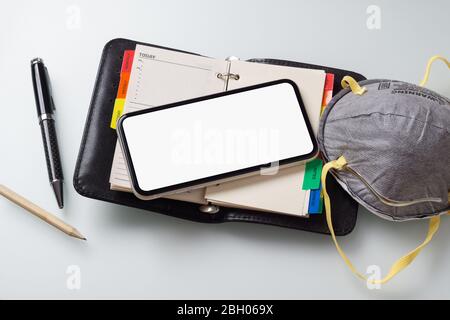 Mockup bianco schermo smartphone su notebook business con N95 facemask per Coronavirus o Covid-19 focolaio Mock up. Foto Stock