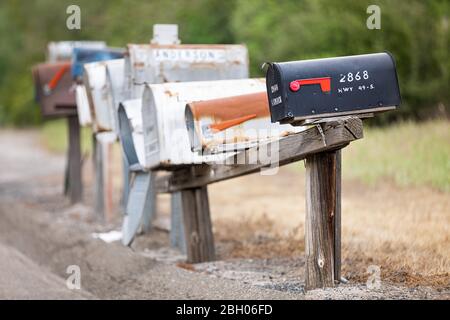 Primo piano di una lunga fila di vecchi e arrugginiti cassette di lettere americane sul marciapiede Foto Stock