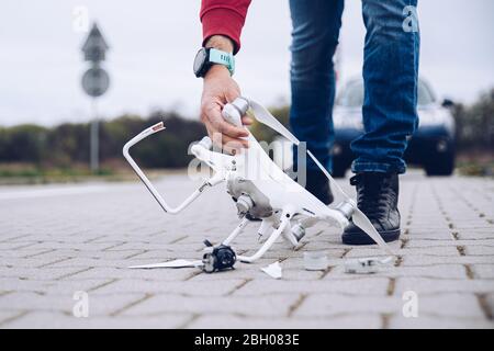 Scioccato uomo preoccupato dopo il suo drone crash. Distrutto drone rotto Foto Stock