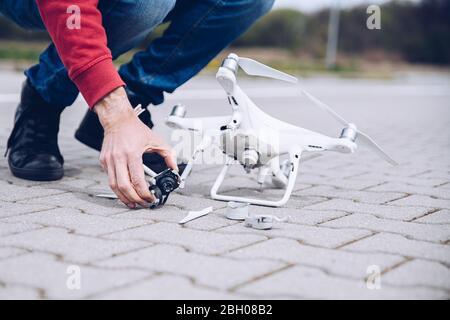 Scioccato uomo preoccupato dopo il suo drone crash. Distrutto drone rotto Foto Stock